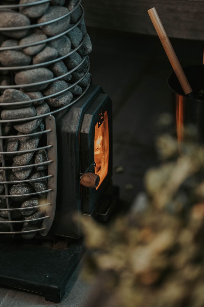 our-journey-03 Warm ambiance with a sauna stove and stone heater creating a cozy firelight atmosphere.