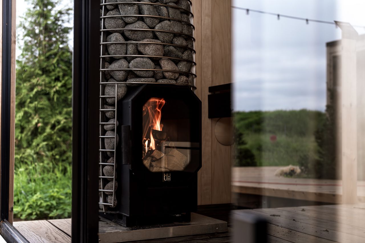 services-02 A stylish sauna interior featuring a modern stone heater with a view of lush greenery.