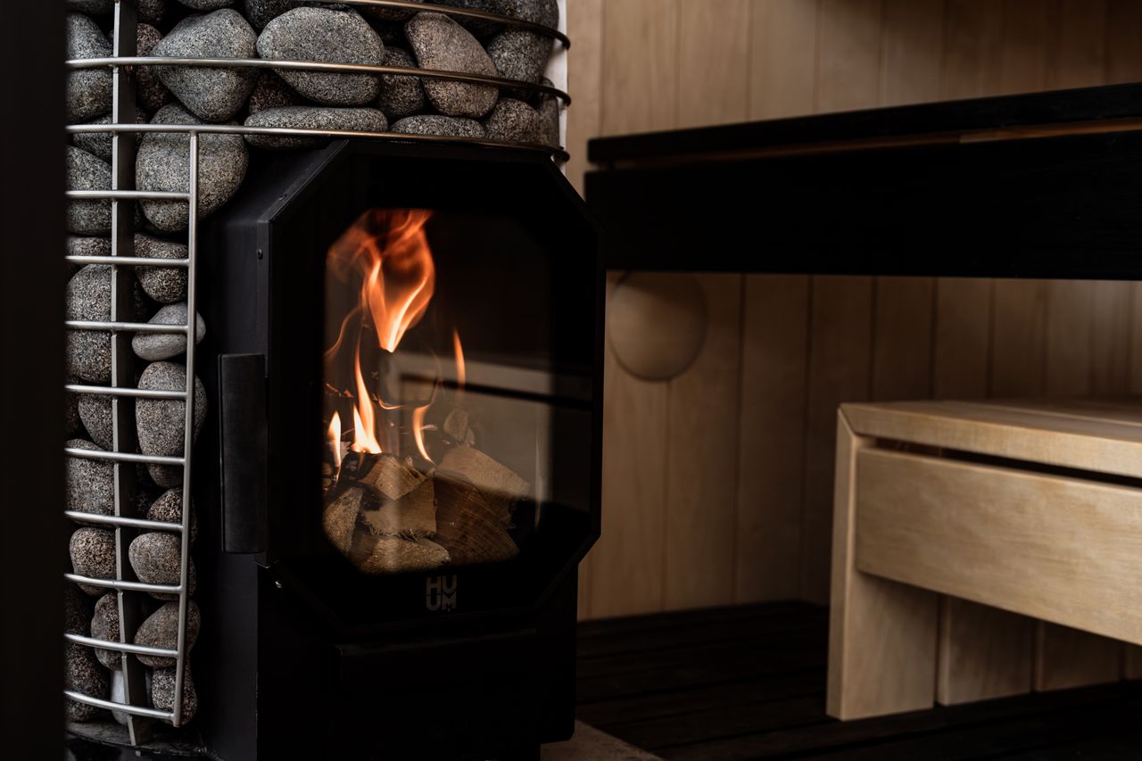 services-01 Wood-fired sauna with stone heater exemplifying Nordic design and relaxation.